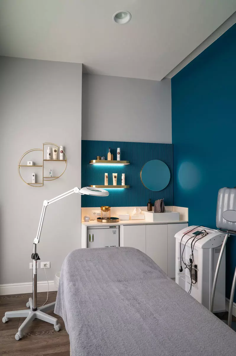 Interno di un centro estetico moderno, con parete blu, scaffali dorati espositivi e attrezzature per trattamenti di bellezza.