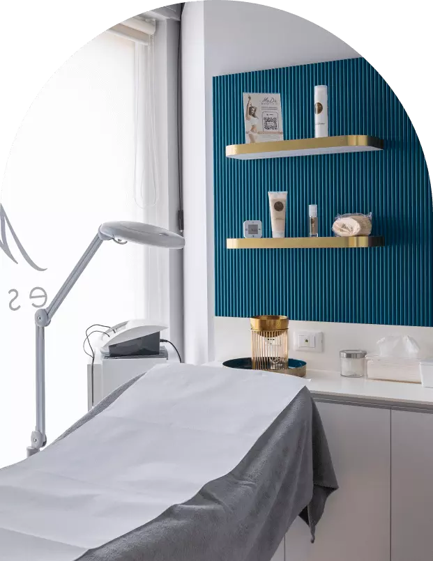 Interno di un centro estetico con una stanza ben arredata, attrezzata per trattamenti di bellezza. Si notano scaffali con prodotti per la cura della pelle.