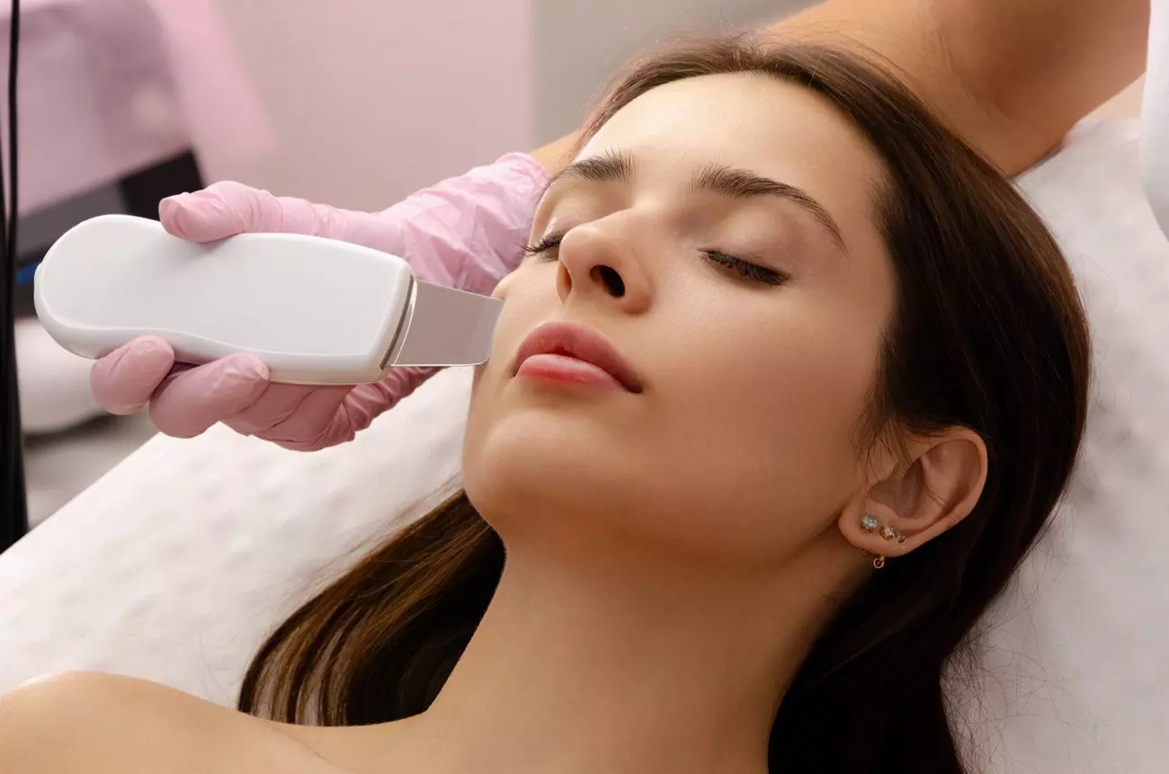 Una donna sottoposta a un trattamento estetico con un dispositivo per la pulizia del viso, in un ambiente rilassante e professionale.